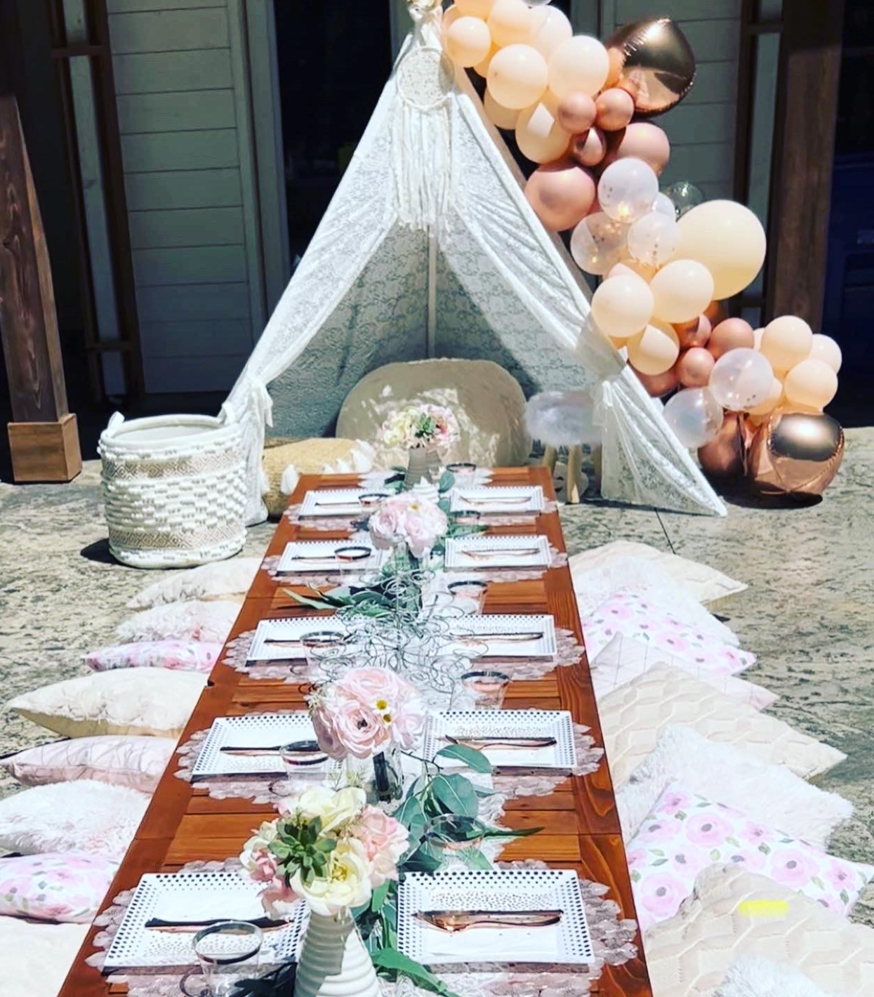 Styled picnic table with floral place settings, cushions and lace tent