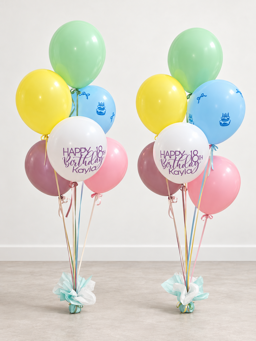 Two personalized pastel birthday Signature balloon bouquets with satin ribbons and mint tissue-wrapped weights